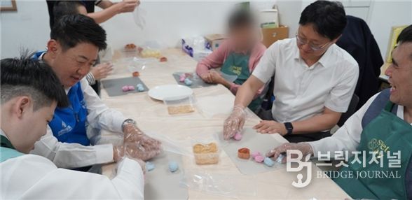 박지훈 신한은행 인천금융센터 지점장과 최진산 부지점장이 지난 1일 미추홀푸르내에서 거주 장애인들과 송편을 빚고 있다.