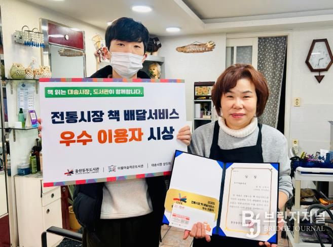 대송시장 헤어세상 심영미 사장이 동부도서관이 주관한 '전통시장 책 배달 프로그램' 우수이용자상을 받고 기념사진을 찍고있다