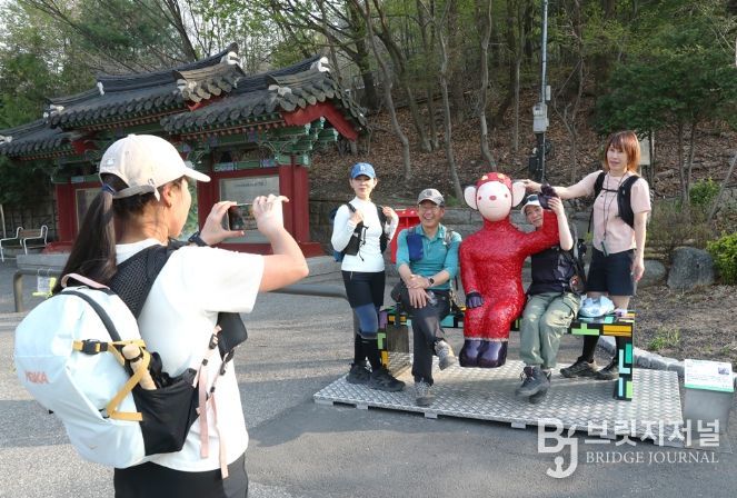 관악산 등산로 입구 으뜸공원에 설치된 작품 ‘하이’와 함께 기념사진을 촬영하는 등산객들