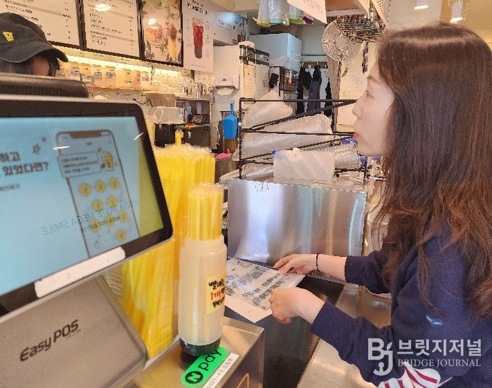 화산동 관계자가 카페를 방문해 종이팩 별도 수거 사업을 홍보하며 전용 수거 봉투를 전달하고 있다